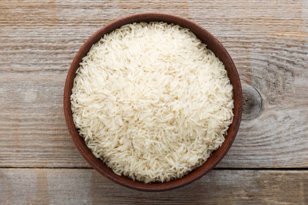 istock raw long rice in a plate on a wooden table. 1055222496