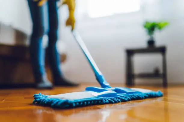 Close-up of young woman mopping the floor