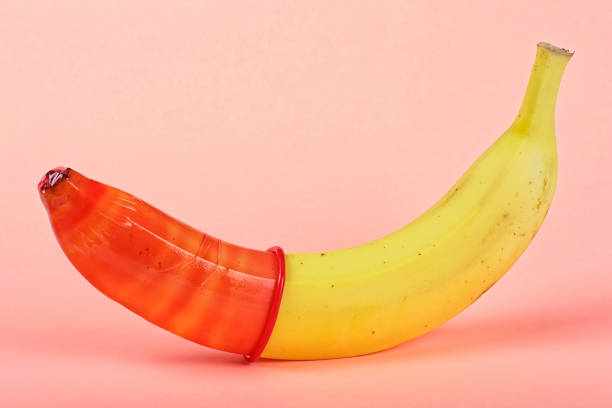 istock Yellow banana with red condom on a pink background 1055232470