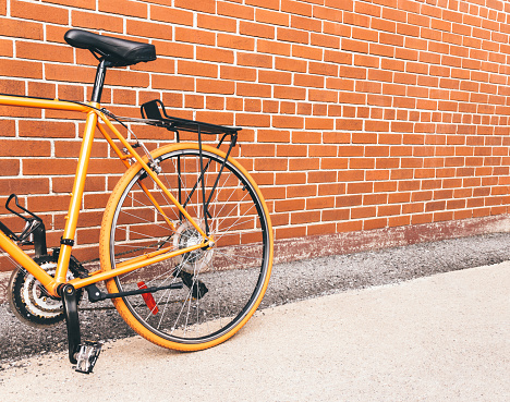 Urban orange bicycle near red brick wall with copy space. Montreal, Quebec (Canada).