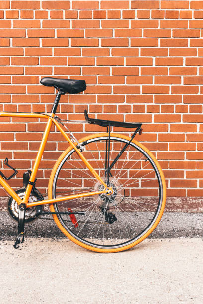 istock Stylish orange bicycle near red brick wall 1055235632