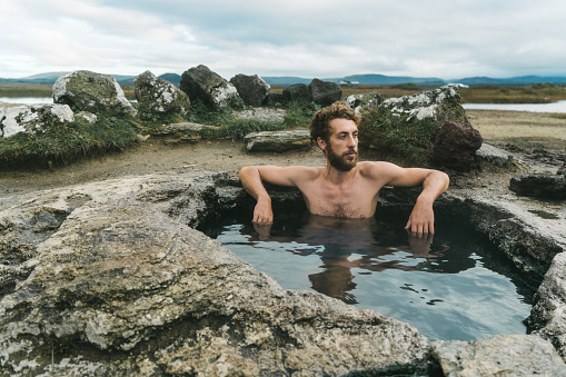 Young Caucasian man  in hot pool in Iceland
