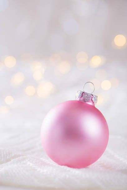 istock Pink Christmas ball on white lace on light and warm bokeh background 1055247498