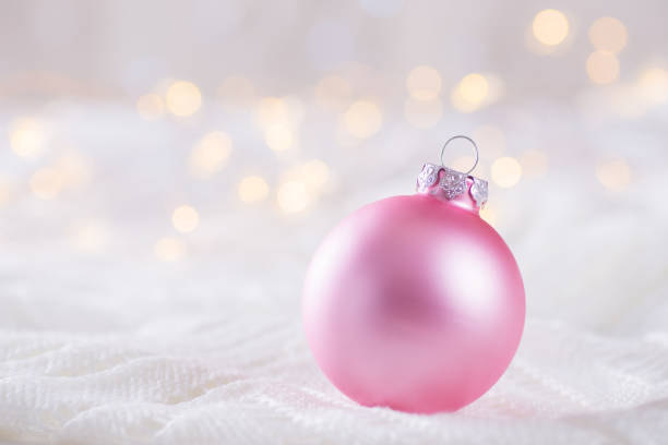 istock Pink Christmas ball on white lace on light and warm bokeh background 1055247524