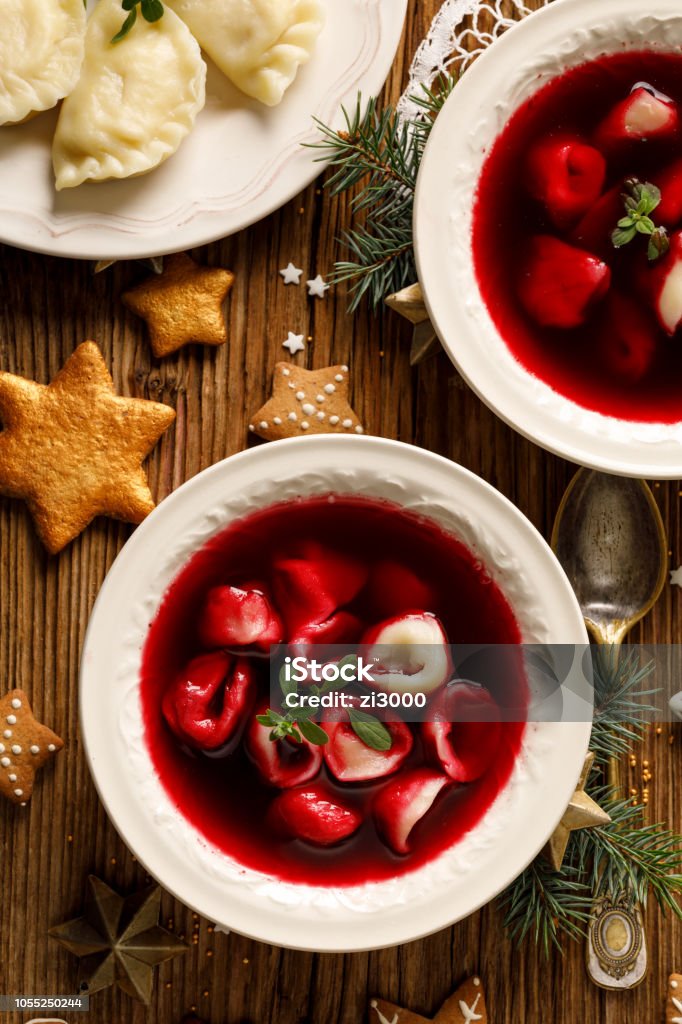 Christmas beetroot soup, borscht with small dumplings with mushroom filling in a ceramic bowl on a wooden table. Christmas beetroot soup, borscht with small dumplings with mushroom filling in a ceramic bowl on a wooden table.  Traditional Christmas eve dish in Poland. Christmas Stock Photo