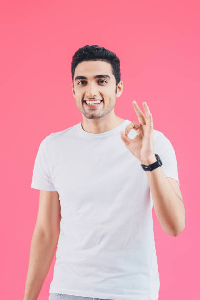 istock happy handsome man showing okay gesture isolated on pink 1055255642