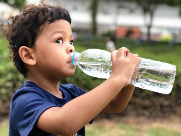 istock Close-Up Of Cute Boy Drinking Water 1055256440