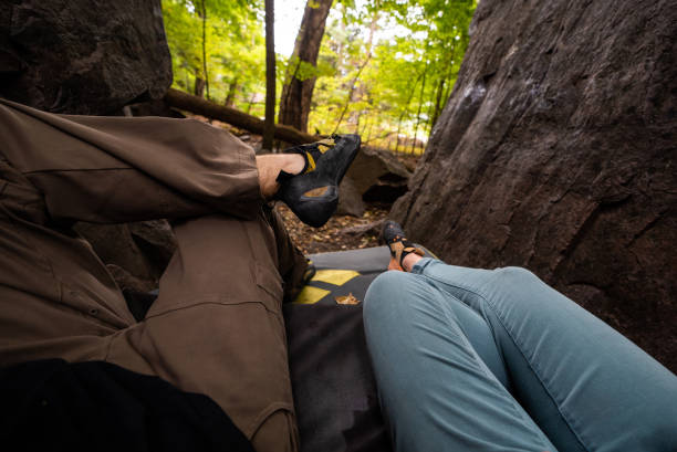 istock Active Rock Climber Couple Resting on Boulder pad in Forest in Autumn Between Rocks on the Ground with Climbing Shoes Relaxing. Devils Lake Wisconsin 1055260772