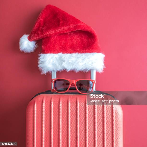 Lay Piatto Di Cappello Di Babbo Natale Occhiali Da Sole E Bagagli Astratti Isolati Sul Rosso - Fotografie stock e altre immagini di Natale