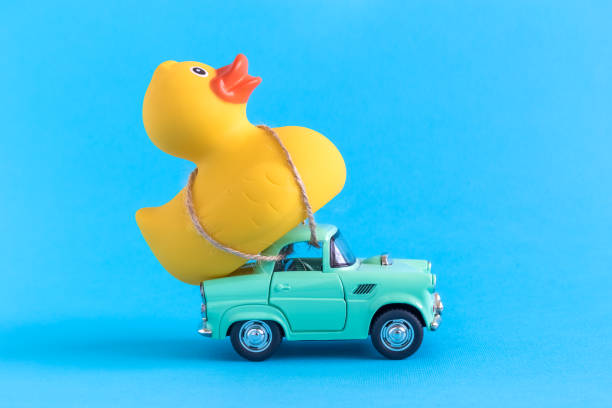 Rubber duck and small car toys abstract isolated on blue.