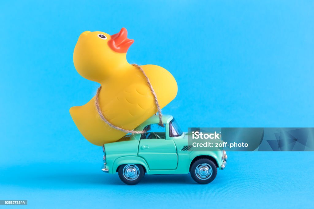 Rubber duck and small car toys abstract isolated on blue. Car and rubber duck on blue background summer vacation minimal creative concept. Humor Stock Photo