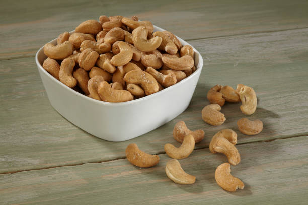 istock Cashew in white bowl on wooden background 1055277636