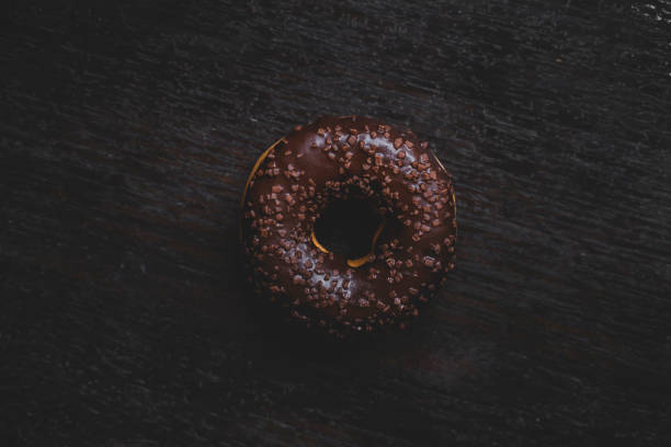 American style donut pastry with chocolate flavour on a wooden table.