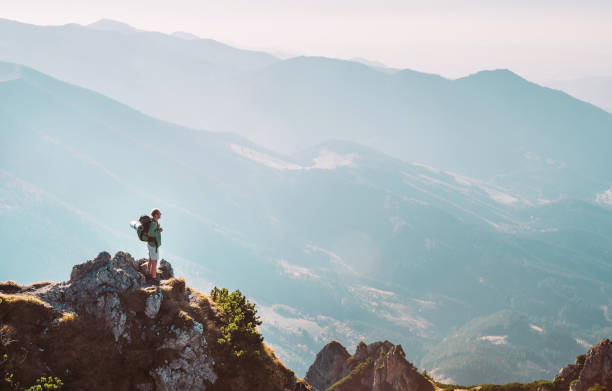 istock Mountain hiker with backpack tiny figurine stay on mountain peak with breathtaking hills panorama 1055287102