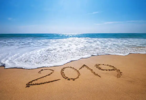 Photo of Happy New Year 2019 is coming concept sandy tropical ocean beach lettering concept image and