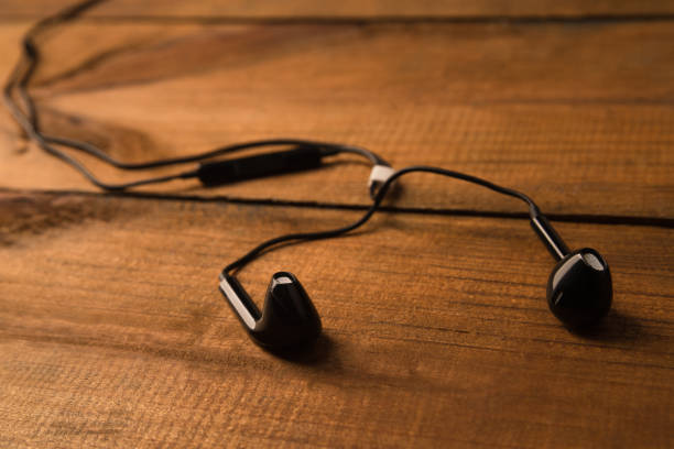 istock Black little headphones on a wooden isolated background. Horizontal frame 1055288556