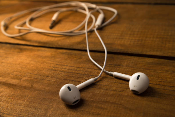 istock White little headphones on a wooden isolated background. Horizontal frame 1055288714