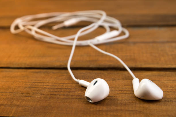 istock White little headphones on a wooden isolated background. Horizontal frame 1055288804