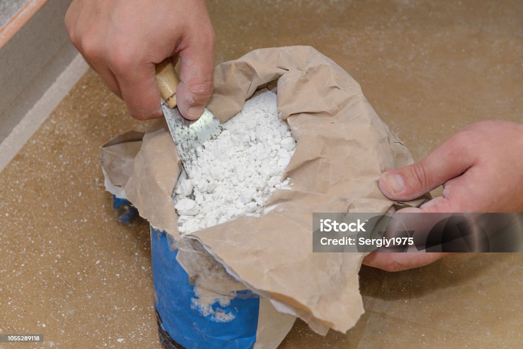 travailleur prend une spatule albâtre dans un sac - Photo de Plâtre - Matériau de construction libre de droits