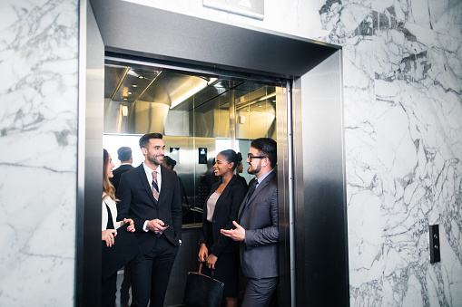 A young group of latin millennial executives discussing work and laughing in an elevator