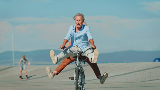 Senior couple riding tandem bike with legs apart
