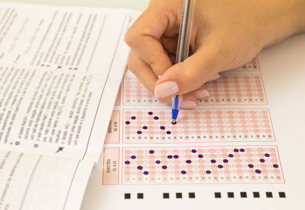 Female hand with pen filling multiple choice test. Optical form of an examination. (translation: number of questions) Conceptual image for education, vestibular, middle school, public education, university, college, distance education. exam student university writing stock pictures, royalty-free photos & images