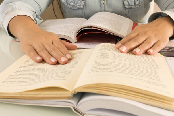 istock Female student hand on books and desk, studying. 1055304032