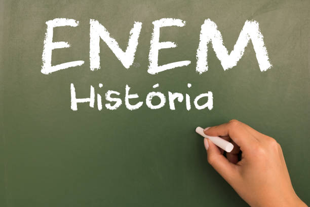 istock Female hand writing with chalk on empty green chalkboard. (translation portuguese: ENEM - National High School Exam Brazil - history) 1055304240