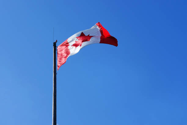 istock Canadian flag in blue sky background 1055308090