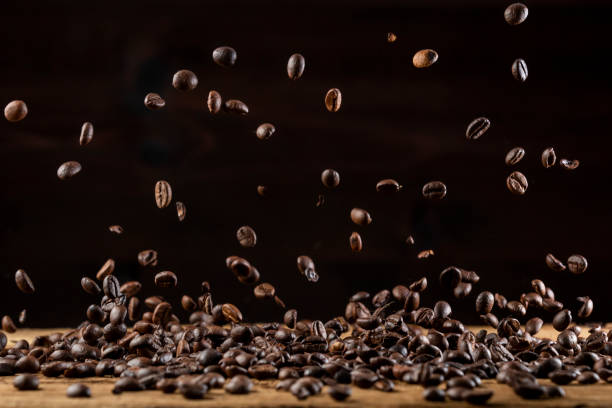 geröstete kaffeebohnen herunterfallen auf holztisch - falling beans stock-fotos und bilder