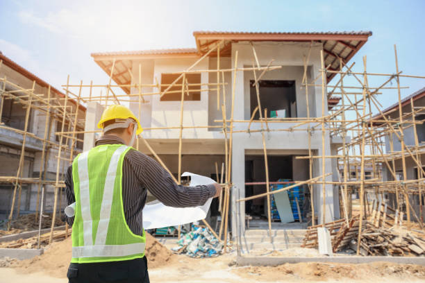 istock Professional engineer architect worker with protective helmet and blueprints paper at house building construction site 1055312266