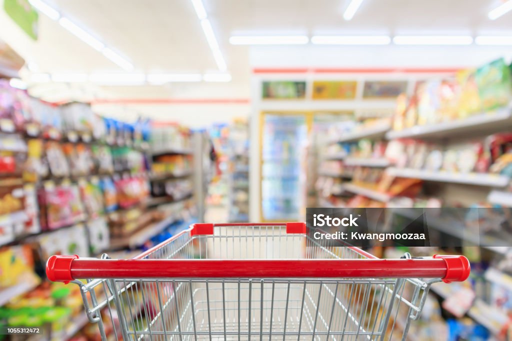 Shopping cart with Supermarket convenience store aisle shelves interior blur for background Supermarket Stock Photo