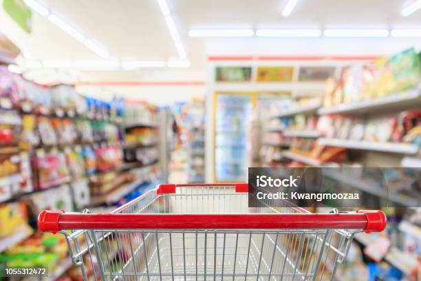 Shopping Cart With Supermarket Convenience Store Aisle Shelves Interior Blur For Background Stock Photo - Download Image Now