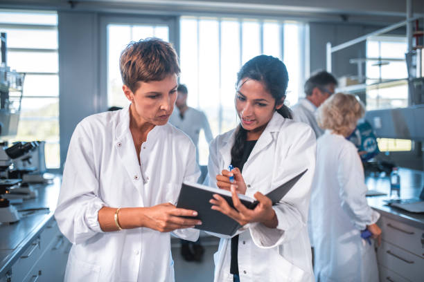 istock Chemist discussing with colleague holding diary 1055312560