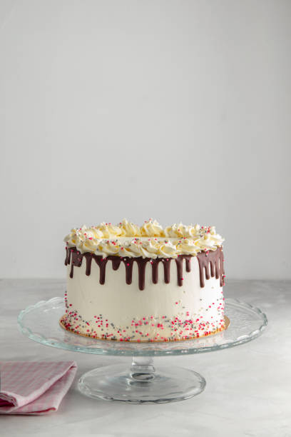 istock Easy Birthday Drip Cake with chocolate ganache and sprinkles on a white background with party decor. Vertical. Copy space. Celebration concept. Trendy Drip Cake. 1055343770