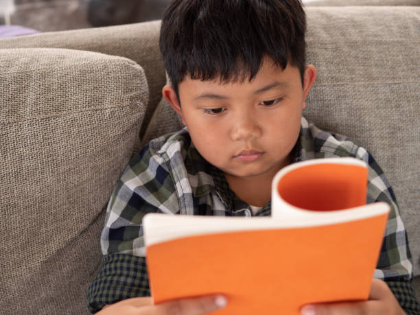 istock Cute asian children reading a book while on a sofa in the room. education concept 1055350162