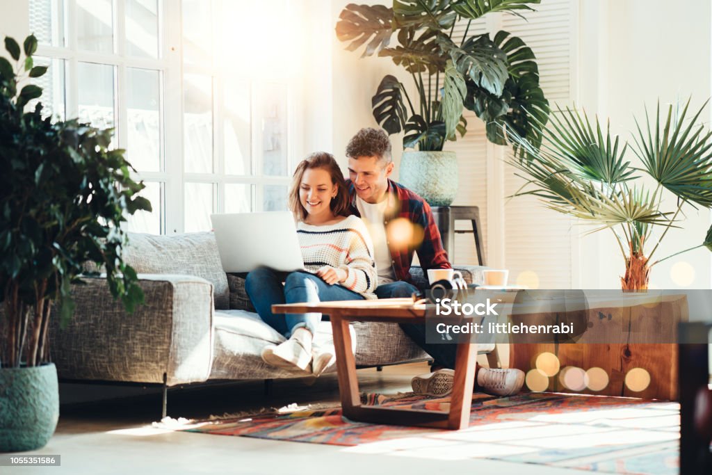 Family relationship. Happy couple at home on the couch Couple in love. Happy family watching TV series using laptop and sitting on the couch Couple - Relationship Stock Photo