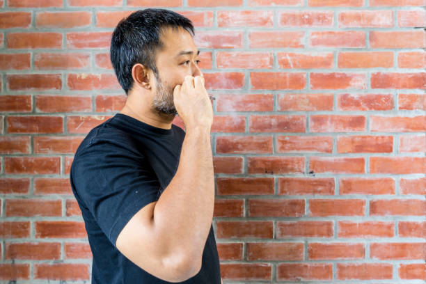 asian bearded man while smoking cigarette brick wall background stock photo