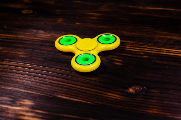 istock Yellow fidget spinner on wooden desk 1055369498