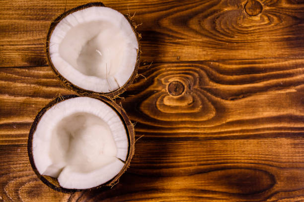 istock Ripe halved coconut on a wooden table. Top view 1055371042