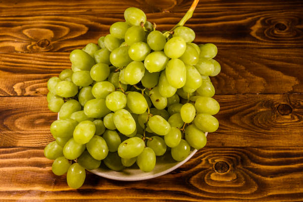 istock Ceramic plate with green grapes on wooden table 1055371096
