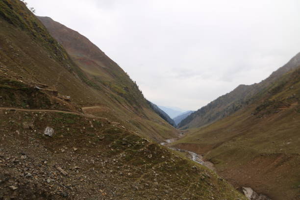 istock Track and river passing through between the big mountains under cloudy sky 1055371138