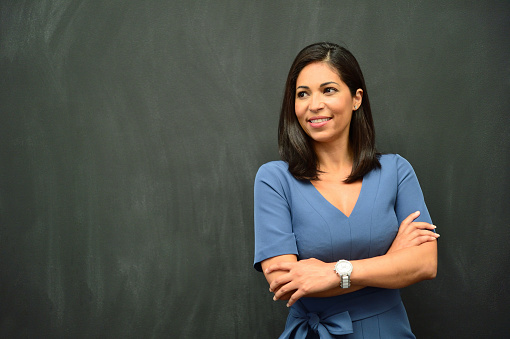 Strong Hispanic Woman standing in front of blackboard. Copy space.
