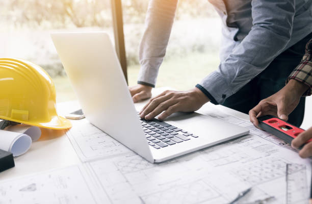 istock Architect discussing new project and using laptop with colleague in office. 1055392690