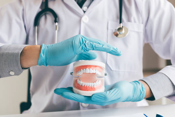 istock Man dentist asian hand protecting the dentures. 1055392836