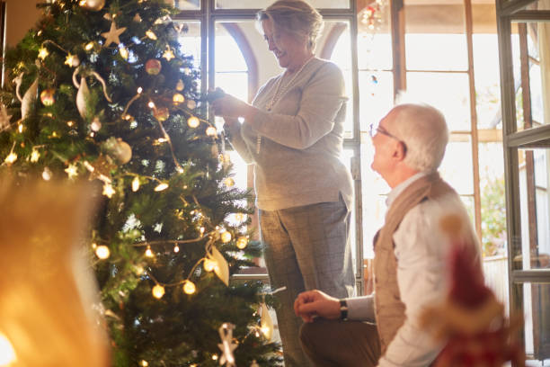 istock Senior couple decorating the christmas tree at home. 1055406896