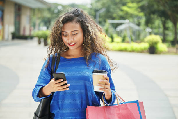 istock Indonesian female with hot beverage using smartphone during shopping 1055412896