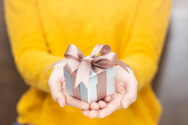 Young woman in yellow sweater holding gift box for spacial event. Young woman in yellow sweater holding gift box for spacial event. Christmas, birthday, valentine's background concept. birthday present photos stock pictures, royalty-free photos & images
