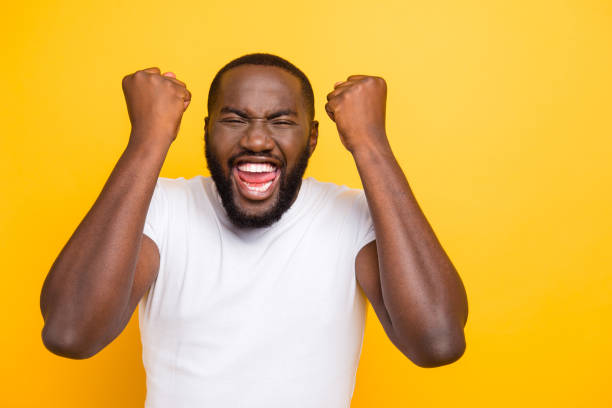 istock Handsome attractive manly cheerful glad crazy man, showing winning yes cool gesture, celebrating, opened mouth, isolated over bright vivid yellow background 1055426602