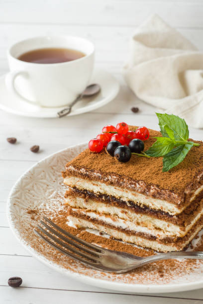 istock Delicious Tiramisu cake with fresh berries and mint on a plate on a light background. Breakfast with a Cup of coffee. 1055426714